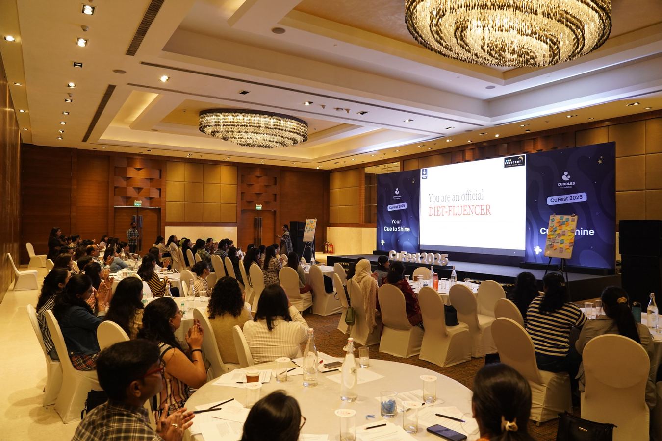A full ballroom of participants applauding during a PROSCENT session
