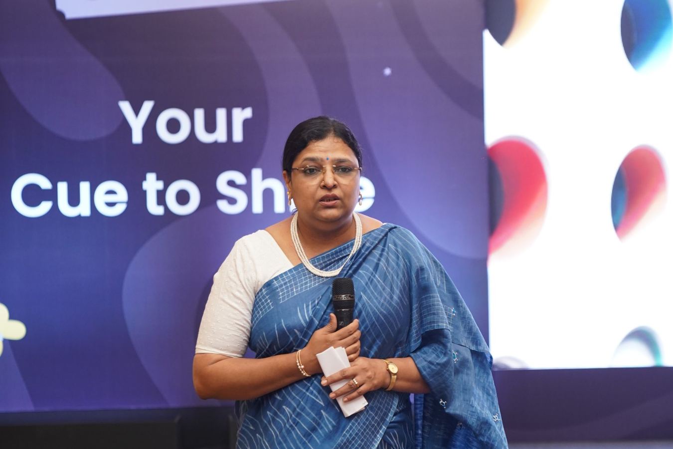 Padmini speaking on stage with a microphone